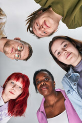 Wall Mural - Portrait of diverse group of young adults looking up towards camera smiling in casual clothing against light background creating an inclusive and friendly image