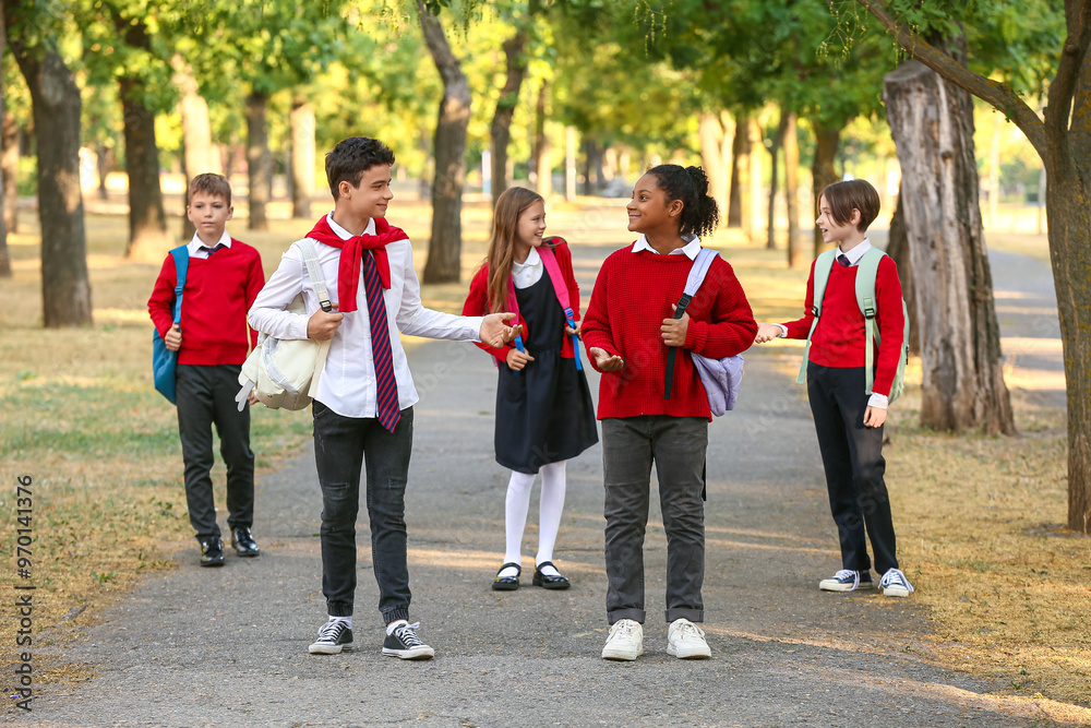 Group of happy pupils speaking while going to school outdoors