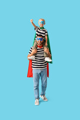 Canvas Print - Happy father with his little son dressed as superheroes having fun on blue background