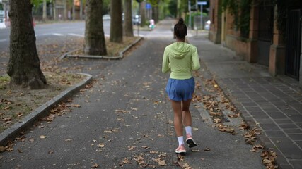 Wall Mural - A woman is jogging in the park during the beautiful autumn season with vibrant leaves