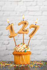 Wall Mural - Cupcake with number 127 birthday candle - White block wall background