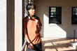 © wavebreak3 - At school, Asian teenage boy with headphones leaning on railing, holding skateboard, enjoying break
