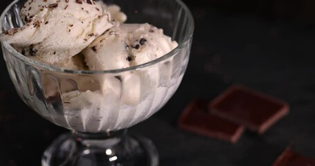 Wall Mural - white creamy ice cream with pieces and crumbs of chocolate in a glass bowl, several balls of ice cream with chocolate