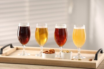 Canvas Print - Glasses with different types of beer and snacks on wooden table indoors