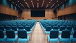 © SC-7 - A vacant conference hall featuring rows of blue chairs, viewed from the back.