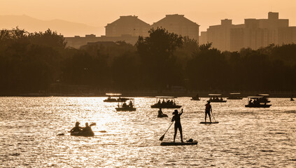 Unrecognized people doing leisure activities in lake during sunset. Beijing, China