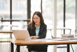 © Kritdanai - Focused and Driven: Businesswoman working on her laptop in a modern office setting, exuding confidence and dedication