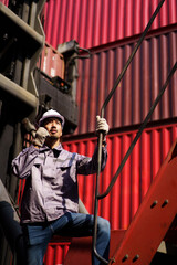 Asian male container yard worker perform an inspection.