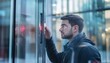 © Mikki Orso - Man unlocks glass office door with facial recognition technology in modern workplace setting