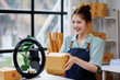 © David - vlogger, blogger small SME business asian beautiful woman using mobile phone video call for sell products online live stream, show product present detail at home office, entrepreneur ecommerce