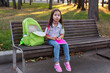 © Natasha  - Young girl with backpack sitting on bench writing in notebook outdoors