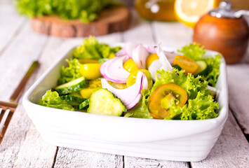 Bright juicy salad with yellow cherry tomatoes and aromatic basil leaves in bowl.