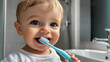 © photoholic - Baby smiling with a blue toothbrush in their mouth, standing in a bright bathroom. Concept of dental hygiene and childhood