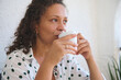 © Taras Grebinets - Relaxed woman enjoying a warm beverage at home wearing a polka dot shirt