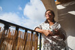 © Taras Grebinets - Woman enjoying morning coffee on sunny balcony in polka dot shirt, feeling relaxed and thoughtful