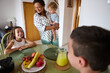 © Taras Grebinets - Happy family enjoying breakfast with fresh fruit and juice in a cozy kitchen, capturing joyful moments of togetherness and bonding.