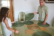 © Taras Grebinets - Children preparing dining table with green placemats in a cozy dining room setting