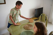 © Taras Grebinets - Young boy and girl preparing dining table with placemats in a cozy home setting