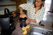 © Taras Grebinets - Woman in dotted shirt making fresh lemon juice using a modern juicer in a cozy kitchen setting