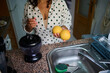© Taras Grebinets - Woman preparing fresh citrus juice in kitchen with lemons and juicer, wearing polka dot shirt for homemade beverage