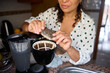 © Taras Grebinets - Woman preparing traditional coffee using a modern coffee maker in the kitchen wearing a polka dot shirt