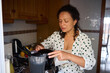 © Taras Grebinets - Woman preparing a healthy smoothie in a kitchen setting with fresh ingredients and a blender