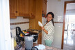 © Taras Grebinets - Smiling woman in kitchen preparing breakfast with fresh ingredients and a recipe sheet in a cozy home setting