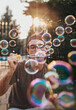 © Cavan Images - Older teen boy blowing soap bubbles outdoors on sunny day.