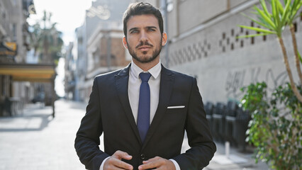 Wall Mural - Handsome hispanic man in suit posing confidently on a sunny urban street, reflecting a professional and stylish appearance.