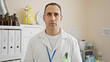 © Krakenimages.com - Portrait of a serious hispanic man in a lab coat standing in a laboratory setting with equipment in the background.