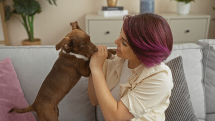 Poster - Young woman playing with her dog in a cozy living room.