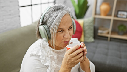 Wall Mural - Senior woman relaxing with headphones and coffee at home