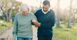 © David/peopleimages.com - Park, walking and caregiver with elderly woman for assisted living, support and care in nature. Retirement, help and man with senior person with disability outdoors for wellness, health and recovery