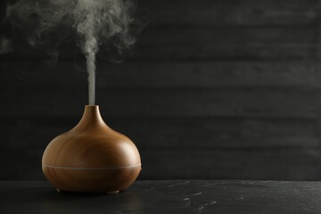 aroma oil diffuser on black table, space for text
