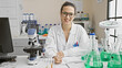 © Krakenimages.com - A smiling hispanic woman scientist writing in a notebook in a laboratory filled with glassware