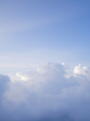 Wall Mural - A serene sky with fluffy white clouds against a light blue backdrop.