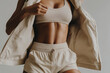 © los_ojos_pardos - An image of a woman wearing a sports bra and shorts, showing her toned abs. She is holding open a jacket, revealing her fit physique.
