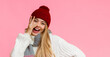 © Prostock-studio - Joyful blonde girl in red hat placing fingers on her face, yellow studio background, panorama with copy space