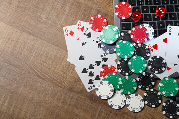 Wall Mural - Online game. Poker chips, laptop, playing cards and dices on wooden table, flat lay. Space for text