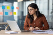 © Liubomir - Serious thinking and concentrated focused business woman behind paper work inside office. An employee of the company compares the data of the report with documents, an accountant, auditor at work.