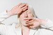 © SHOTPRIME STUDIO - Portrait of a person with long white hair and pale skin, hands raised in a dramatic pose against a light grey background, emphasizing emotion and expression through minimalism
