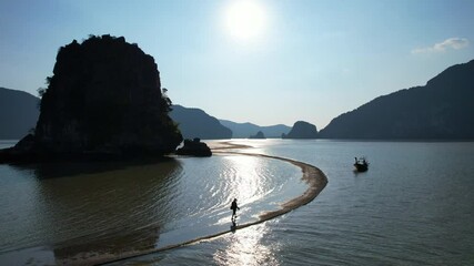 Wall Mural - Tourists walk along a sandbar to enjoy the sunset in Phang Nga Bay, Phang Nga Province, southern Thailand, Asia.