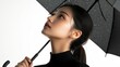 © Suphot - A portrait of a woman holding a black umbrella, gazing upward, showcasing elegance and serene beauty on a white background.
