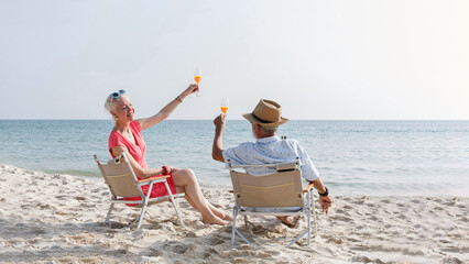 Happy couple caucasian senior woman travel nature ocean relaxing and drink orange juice at tropical beach, Healthy seniors lifestyle, Savings and senior health insurance concept.