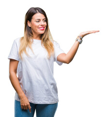 Wall Mural - Young beautiful woman casual white t-shirt over isolated background smiling cheerful presenting and pointing with palm of hand looking at the camera.