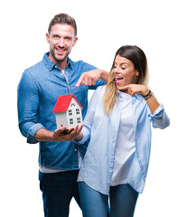 Wall Mural - Young couple in love holding house over isolated background very happy pointing with hand and finger