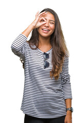 Wall Mural - Young beautiful arab woman wearing sunglasses over isolated background doing ok gesture with hand smiling, eye looking through fingers with happy face.