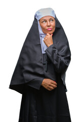 Wall Mural - Middle age senior christian catholic nun woman over isolated background looking confident at the camera with smile with crossed arms and hand raised on chin. Thinking positive.