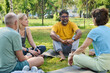 © pressmaster - Smiling mature man in activewear sitting on mat between diverse people and listening to elderly female yoga trainer at break