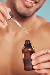 Poster - Skincare, hands and man with serum in pipette, facial treatment product and skin glow on blue background. Cosmetics, retinol liquid and male person with oil, bottle or collagen solution in studio